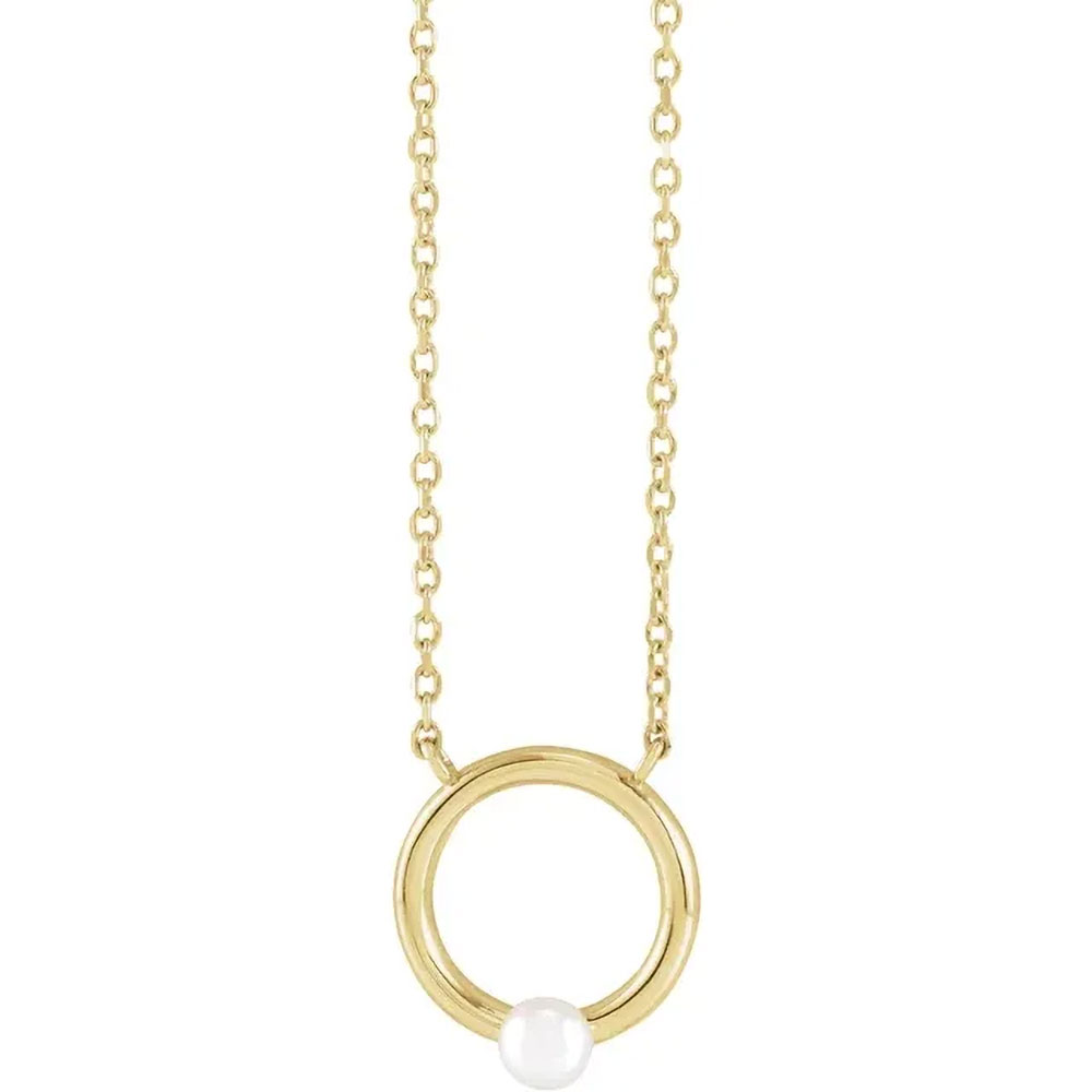 Elegant 14k gold necklace with a central pearl encased in a gold circle, showcasing a blend of classic and modern design.