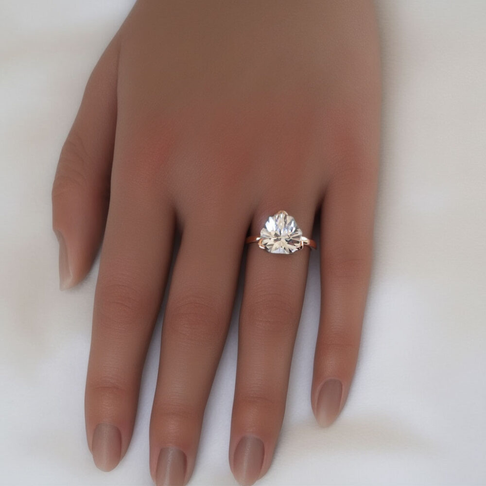 Love's radiance reflected in the sparkle of a lab-created white sapphire engagement ring, displayed here on a hand, set in a 14k rose gold setting.